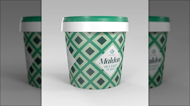 Green tub of Maldon sea salt flakes with white backdrop