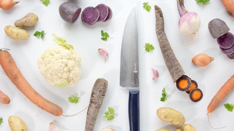 Opinel chef knife on white surface with vegetables