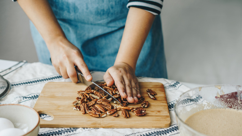 Person chopping nuts on cutting board