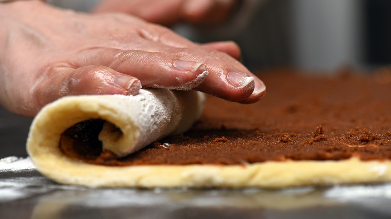 Person rolling cinnamon roll dough