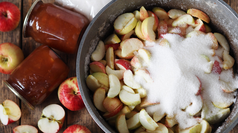 Apples and sugar in pot with cans