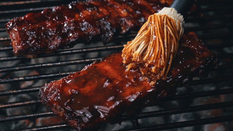 brushing barbeque sauce on meat