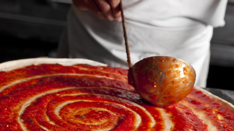 marinara sauce ladled on pizza 