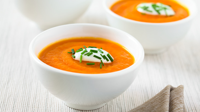 Carrot soup topped with yogurt in white bowl