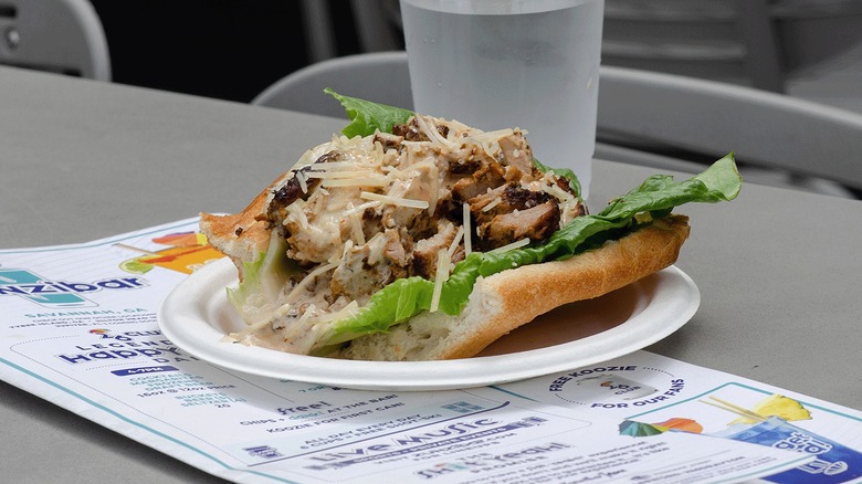 Open sandwich with lettuce, meat, cheese on white paper plate