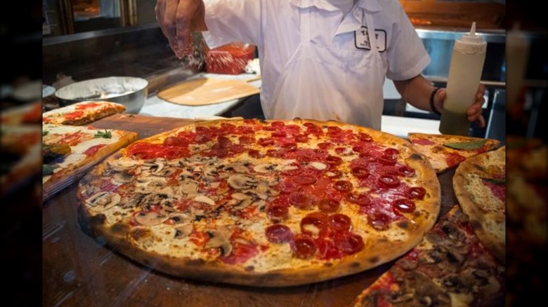 Large New York pepperoni and mushroom pizza on wooden counter