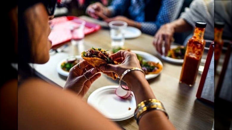 Woman holding taco over white plate