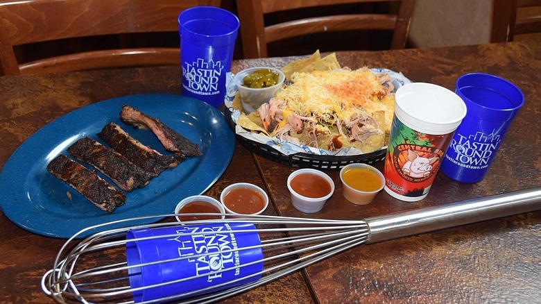 Basket of nachos, sliced beef on blue plate, small sauce cups and blue Tastin Round Town cups on wood table