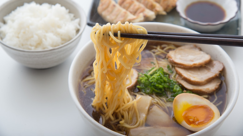 Noodles suspended over a ramen bowl