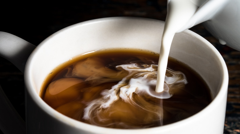 Pouring coffee creamer into coffee