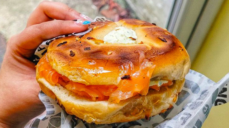 Person holding onion bagel with lox