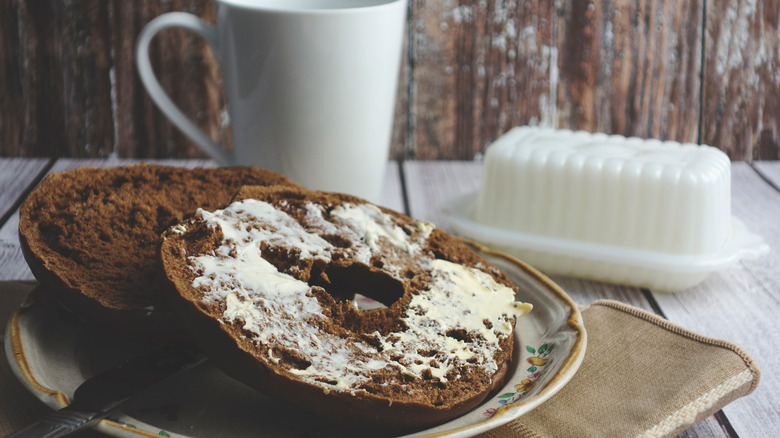 Buttered pumpernickel bagel on plate 