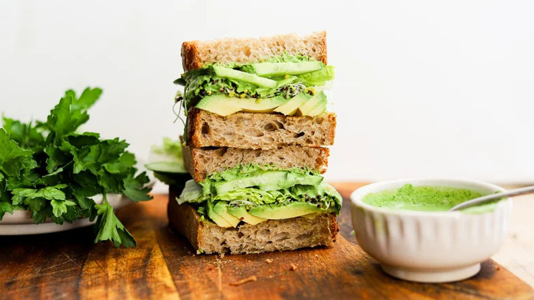 Green Goddess Avocado Sandwich stacked on wooden cutting board