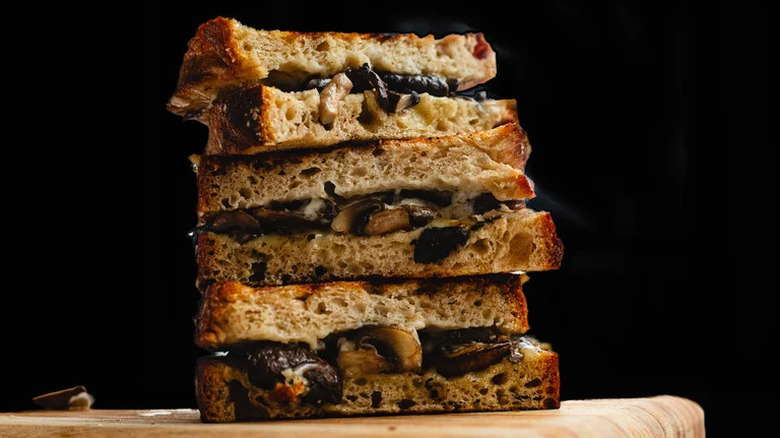 Mixed Mushroom Grilled Cheese stacked on wooden cutting board