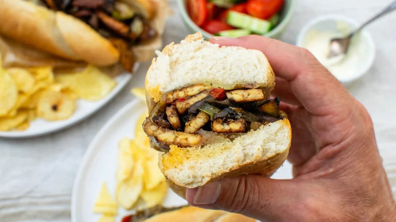 Hand holding Vegetarian Tempeh Cheesesteak