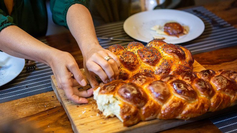 Breaking challah bread on table