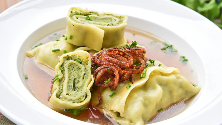 Maultaschen in bowl of broth with one sliced open