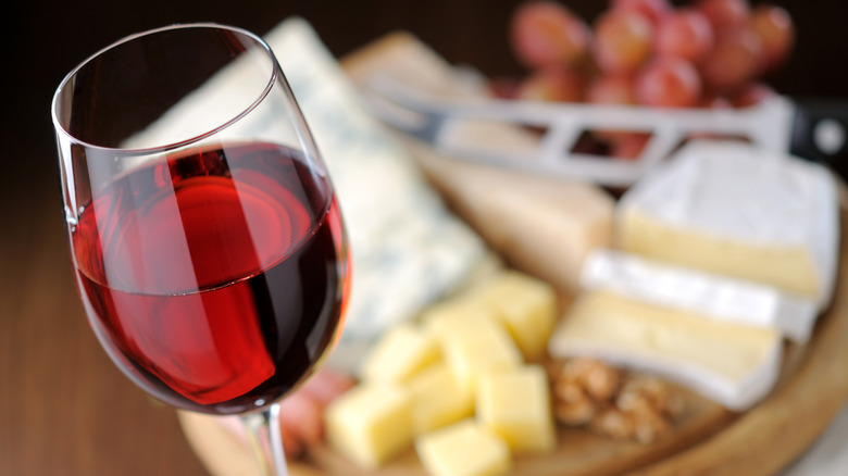 glass of red wine with blurred cheese in background