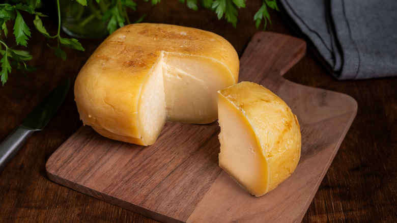 mahon cheese with a wedge cut out on wooden board