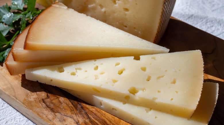 Close-up of sliced Ibérico cheese on a wooden cutting board