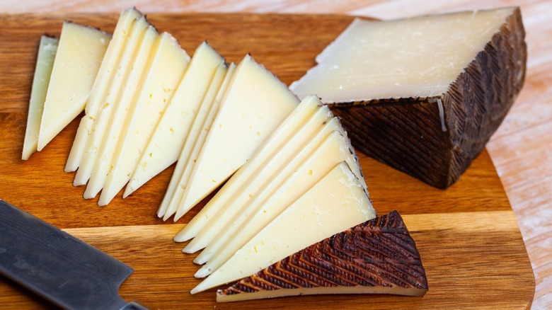 Manchego cheese sliced on a cutting board