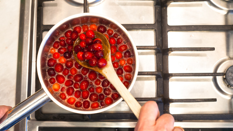 person making cranberry sauce in pot