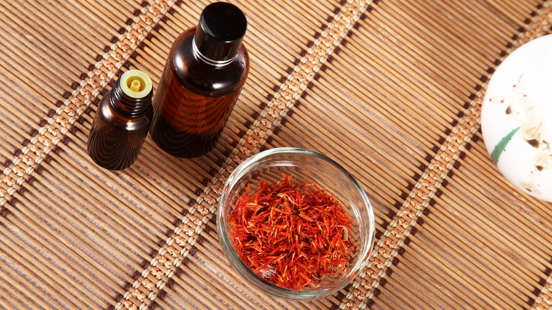 safflower oil bottles and bowl of fresh safflower