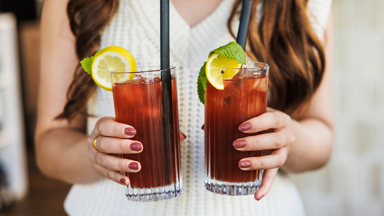 Woman holding two glasses of ice tea with lemon