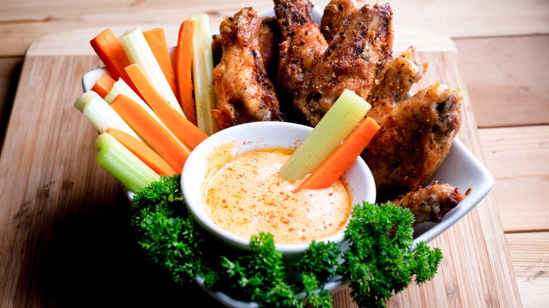 bowl of spicy ranch dip with veggies and wings