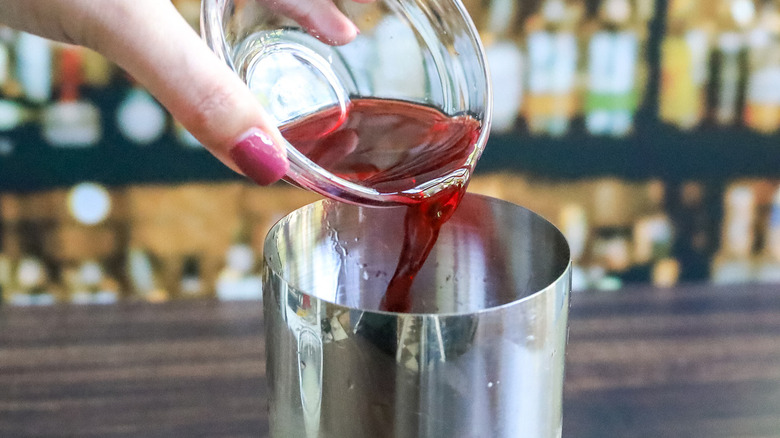 hand pouring juice in shaker