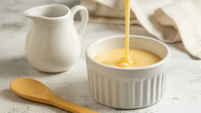 Sweetened condensed milk is being poured into a ramekin.