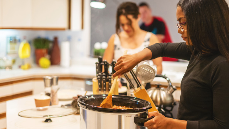 woman stirring food in slow cooker