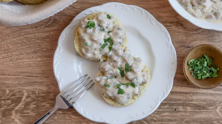Biscuits covered in gravy and herbs on plate
