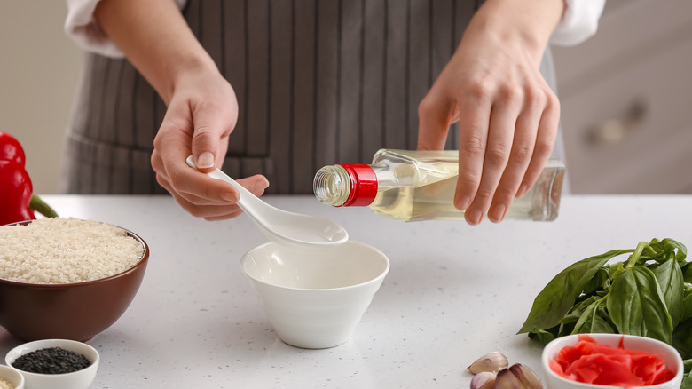 Hands pouring rice vinegar