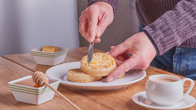 Hands buttering crumpets