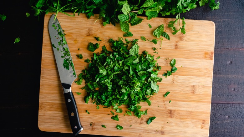 Chef's knife with herbs on cutting board