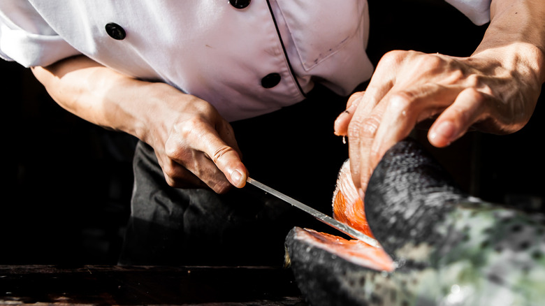 Chef slicing salmon with knife