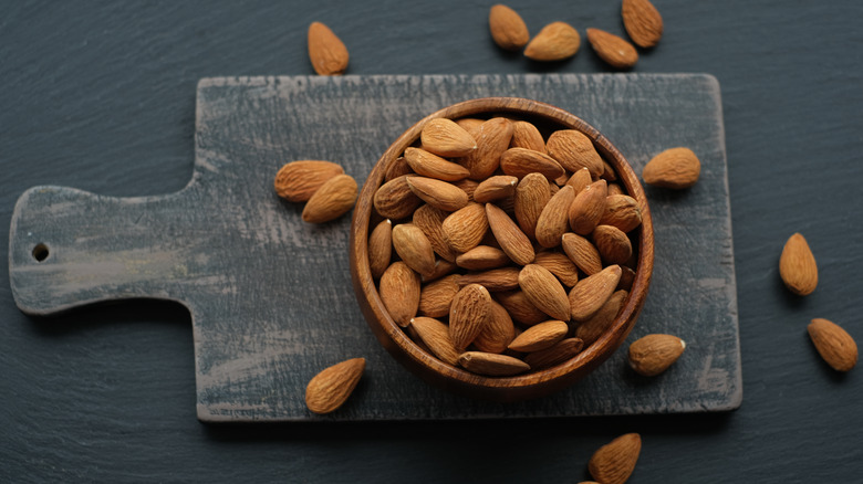 almonds in wooden bowl on board