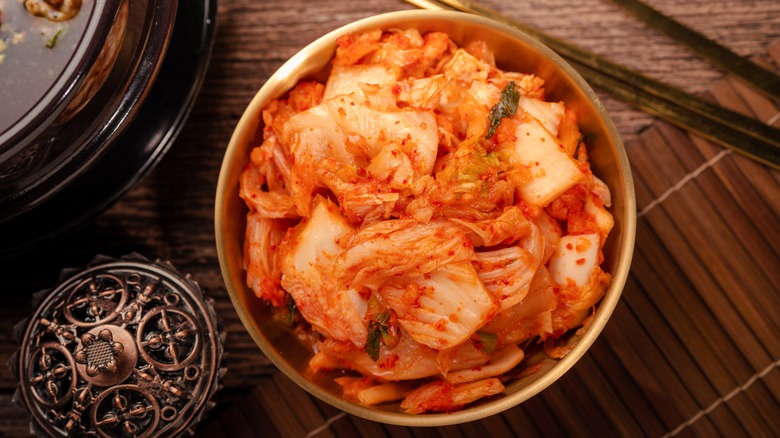 kimchi in a golden bowl with metal chopsticks