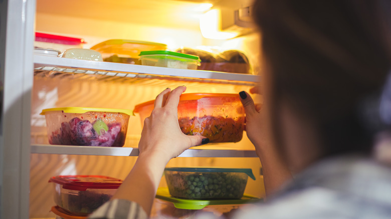 Person picking container in fridge