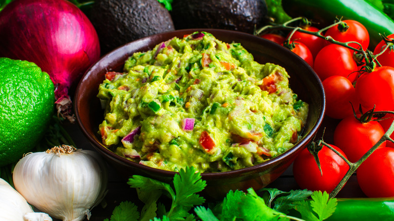 bowl of guacamole surrounded by fresh ingredients