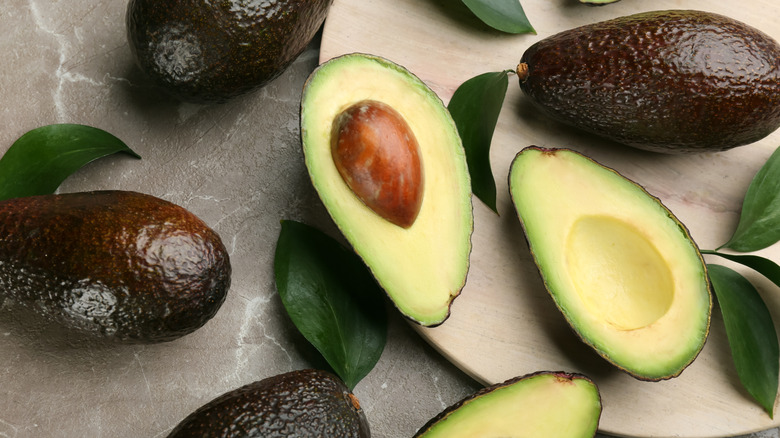 whole avocados and halved avocado showing pit