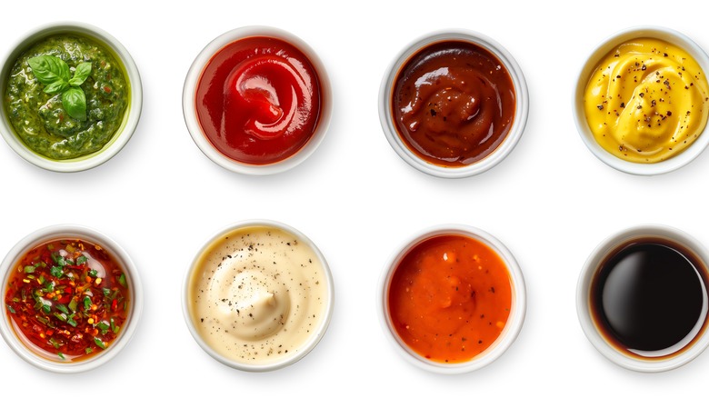 Different sauces in ramekins over white background