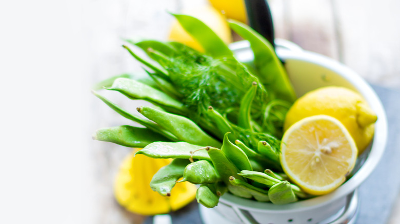 snap peas in a collander with lemons and herbs