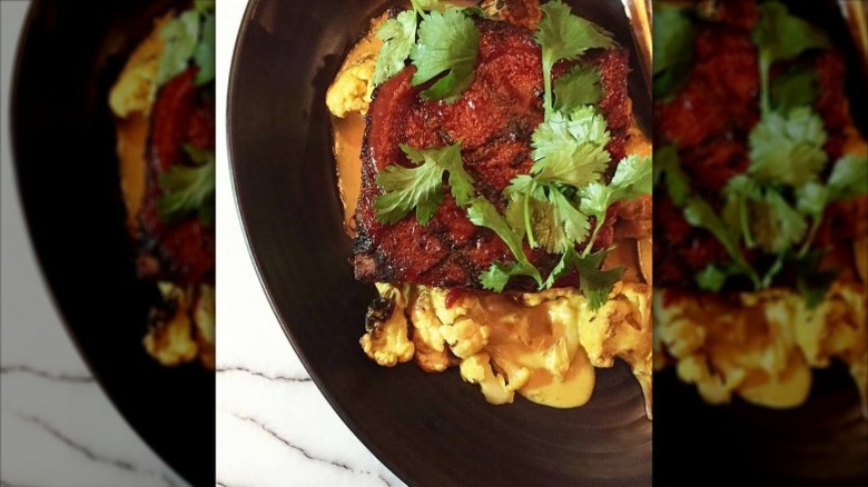 Bacon-wrapped meatloaf on charred curry cauliflower with herbs