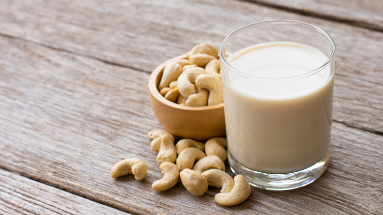 Glass of cashew milk surrounded by cashews