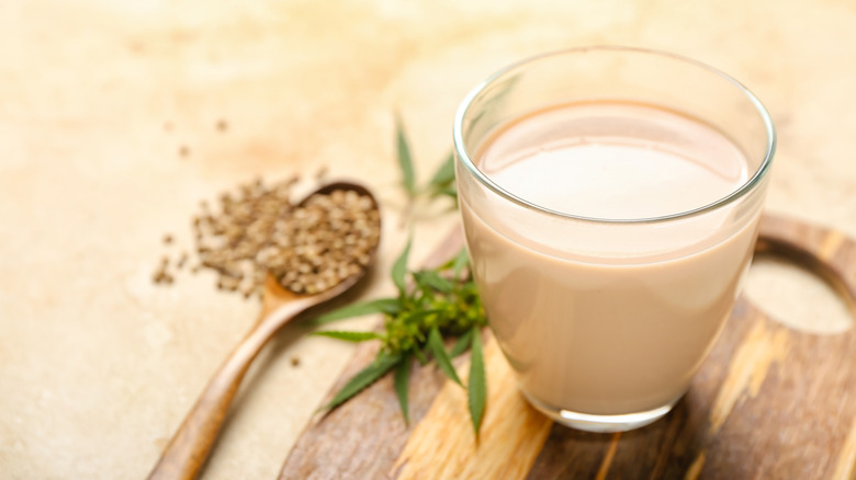 Glass of hemp milk with hemp seeds in background