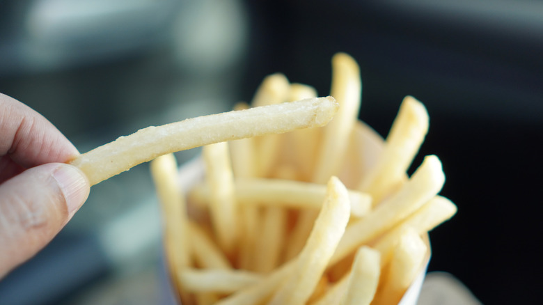A person takes a fry from a box of French fries
