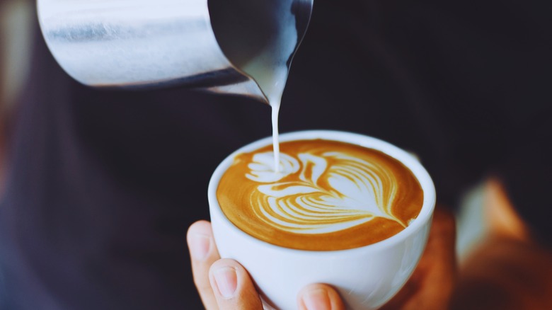 Pouring foamed milk into latte