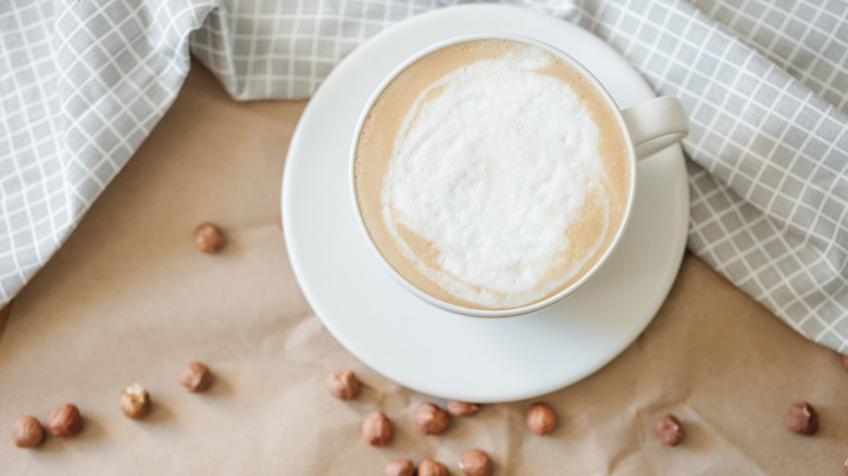 Hot latte in a white cup with smattering of hazelnuts